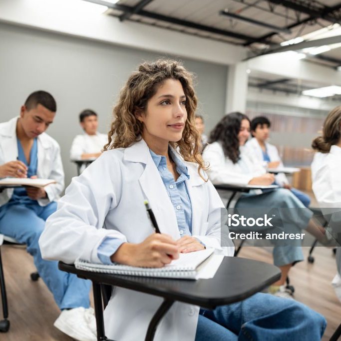 Group of Latin American medical students sitting in the classroom listening to a lecture and taking notes - medical school concepts